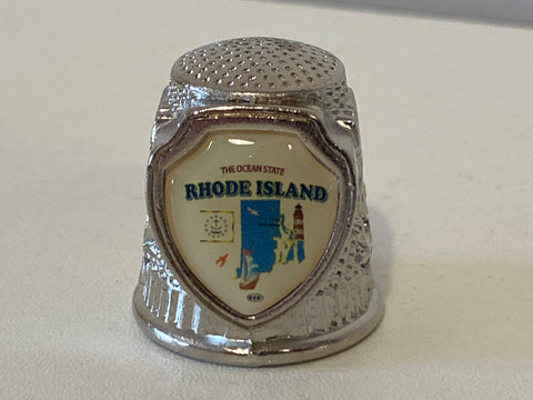 This ceramic thimble features the state of Rhode Island along with a red hen and some flowers. Gold line around the bottom and typical thimble bumps on the top. This is an adorable little addition to your sewing room, or thimble collection!