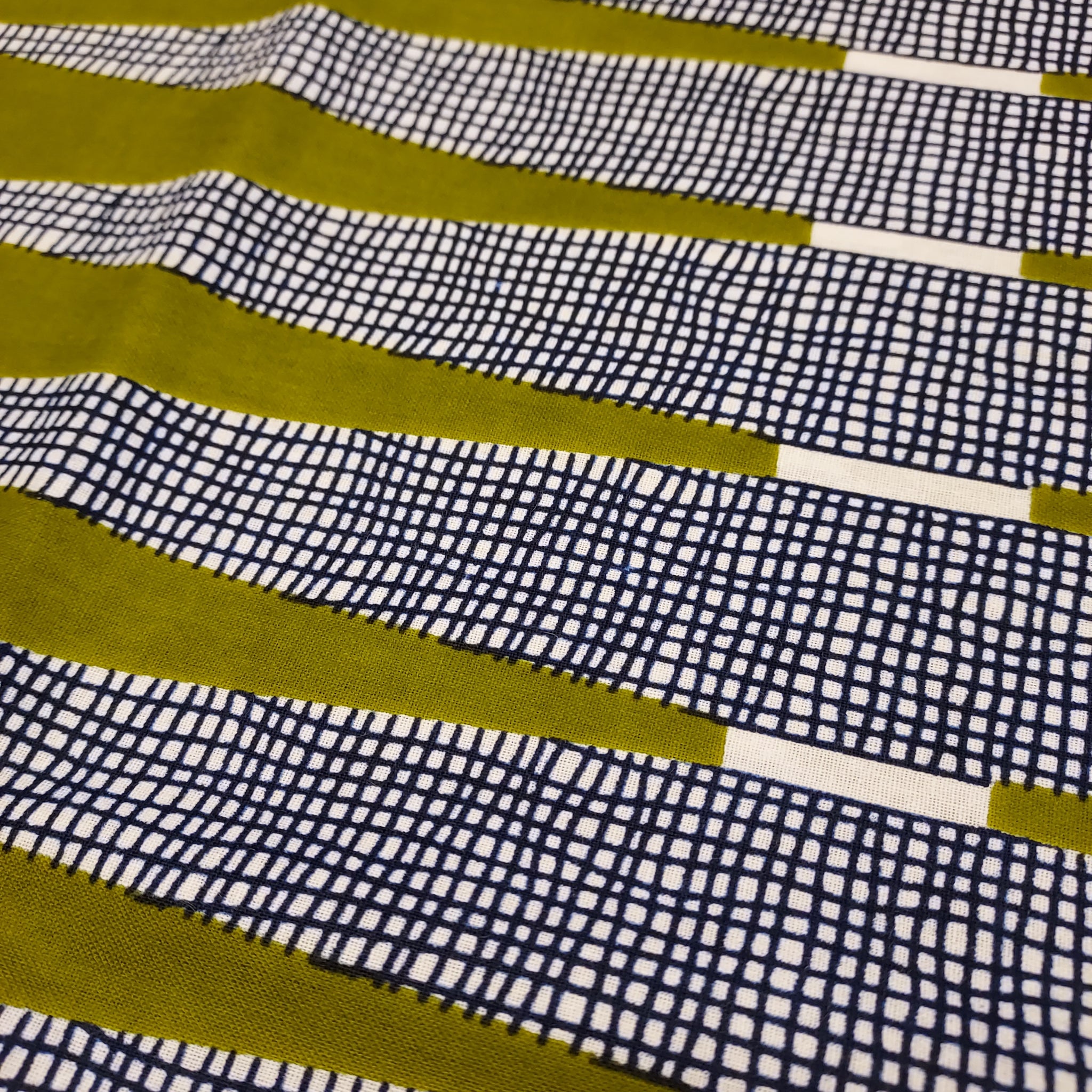 Vibrant olive green with navy cross hatch on a white background. This heavier cotton is a perfect fabric for bottom weight garments, bags, or housewares. This rich olive green is absolutely stunning in person. Triangle design