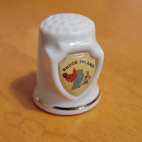 This ceramic thimble features the state of Rhode Island along with a red hen and some flowers. Gold line around the bottom and typical thimble bumps on the top. This is an adorable little addition to your sewing room, or thimble collection!