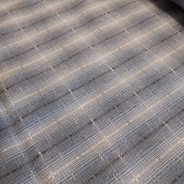 This beautiful woven fabric is made in Japan. Featuring a textured weave, this plaid is blue with navy blue and beige lines throughout. Suitable top or bottom weight. 100% Cotton, 44" wide.