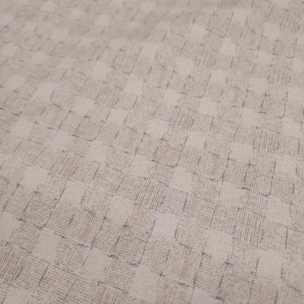 This beautiful cotton fabric is made in Japan. Soft hand and lightweight feel, this fabric has a light taupe background with a taupe and blue grid pattern on top. The grid pattern almost looks like a loose basket weave. This fabric is beautiful and would be suitable for quilting or apparel sewing.   Variant style (CE10472S-A)