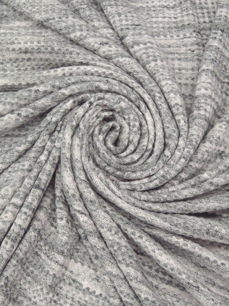 ﻿This is a heathered brushed sweater knit that is 60" wide. It is a polyester and lycra blend. The color is a heathered grey and black with some lighter grey. It has a 4 way stretch that is 70% selvage to selvage. Fuzzy hand which makes it super cozy. 