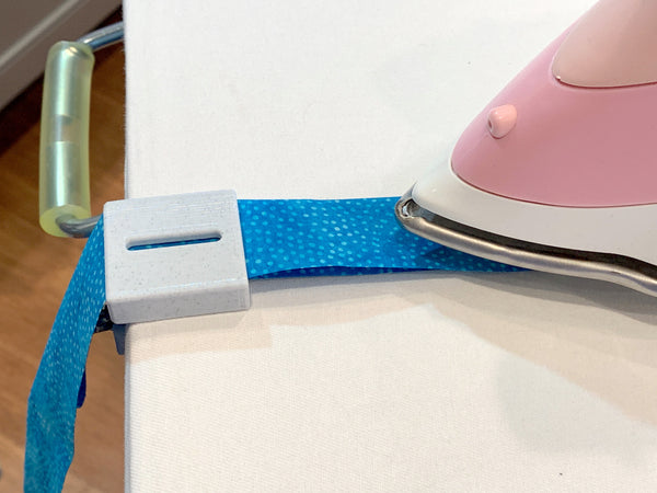 Making binding is easy with the 3rd Hand Binding Clip. It is adjustable so it fits a standard ironing board as well as thinner boards. No tools necessary, just loosen the wing nut, slide the 3rd Hand Binding Folder Clip into place and turn the wing nut to secure it in place.